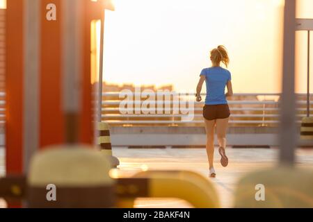 Jeune femme faisant un exercice physique au niveau du parking dans la ville au coucher du soleil Banque D'Images