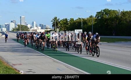 Key Biscayne, Floride - le 15 mars 2020 - un grand groupe de cyclistes entrent à Key Biscayne avec la ville de Miami en arrière-plan en début de matinée. Banque D'Images
