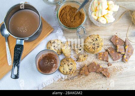Chocolat chaud épicé avec bâton de cannelle et cookies aux pépites de chocolat sur fond en bois Banque D'Images