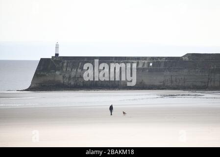 Porthcawl, Pays de Galles du Sud. 28 mars 2020. Un homme marche seul avec son chien à Porthcawl dans le sud du Pays de Galles alors que le Royaume-Uni est arrêté et des mesures de distanciation sociale sont mises en place pour essayer de combattre la pandémie de Coronavirus. Crédit : Robert Melen/Alay Live News. Banque D'Images