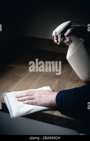 Un gros plan d'une paire de mains humaines nettoyant l'intérieur d'une cuisine avec un spray antibactérien et un chiffon pour désinfecter les surfaces de travail pendant le Cor Banque D'Images