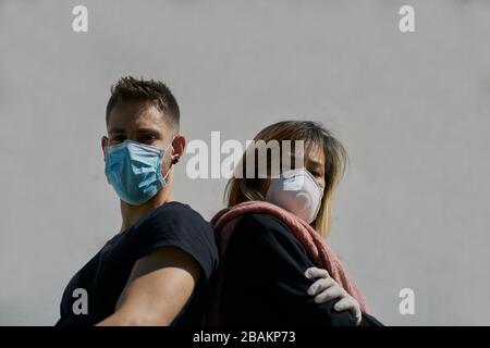 Les hommes caucasiens et les femmes asiatiques portent des masques médicaux comme une défense contre un virus. Le concept de Coronavirus Banque D'Images