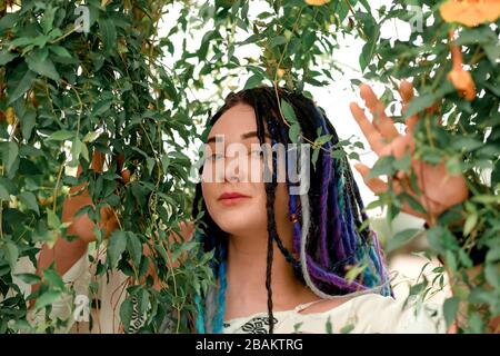 Jolie fille avec des boutons-de-couleur dans une robe blanche se tient sur un escalier rouge dans un arc de fleur, visage, grand portrait. Serre avec t exotique Banque D'Images