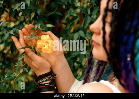 fille avec des readlocks multicolores dans une robe blanche tient une fleur dans ses mains. Serre avec plantes tropicales exotiques dans le jardin botanique de UKR Banque D'Images