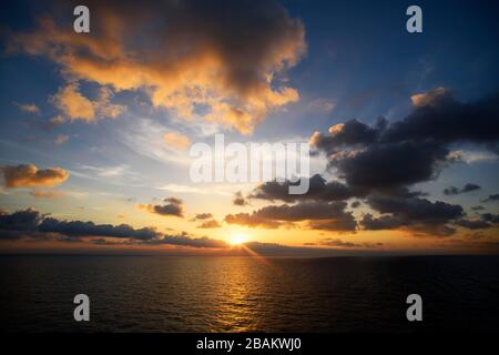 Coucher de soleil nuageux avec soleil clair sous la surface de la mer, tranquillité et calme Banque D'Images