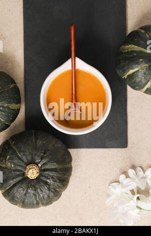 Vue de dessus de la soupe de citrouille dans un bol avec cuillère en bois et décorations Banque D'Images