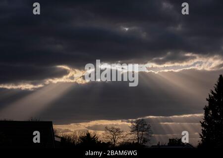 Londres, Royaume-Uni. 28 mars 2020. Après une semaine de beau temps avec ciel bleu, de lourds nuages se déplacent dans le sud-est de l'Angleterre, apportant le temps non réglé. Les rayons crépusculaires, les arbres de lumière du soleil, percent à travers les ruptures dans la couche de nuages en milieu de soirée. Crédit : Malcolm Park/Alay Live News. Banque D'Images