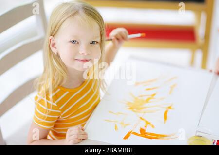 Jolie petite fille dessin avec des peintures colorées. Peinture créative pour enfants à la maison. Éducation et apprentissage à distance pour les enfants. Homeschooling pendant la quarantaine Banque D'Images