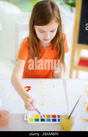 Jolie petite fille dessin avec des peintures colorées. Peinture créative pour enfants à la maison. Éducation et apprentissage à distance pour les enfants. Homeschooling pendant la quarantaine Banque D'Images