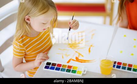 Jolie petite fille dessin avec des peintures colorées. Peinture créative pour enfants à la maison. Éducation et apprentissage à distance pour les enfants. Homeschooling pendant la quarantaine Banque D'Images