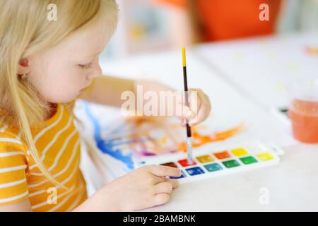 Jolie petite fille dessin avec des peintures colorées. Peinture créative pour enfants à la maison. Éducation et apprentissage à distance pour les enfants. Homeschooling pendant la quarantaine Banque D'Images