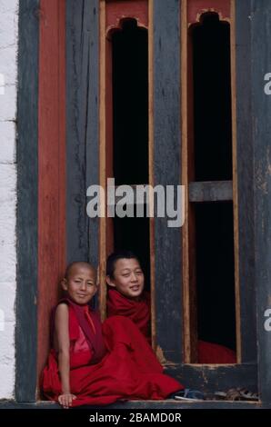 Deux jeunes novitiates de moine trouvent un bon point de vue dans un seuil de fenêtre pour observer les goings à Thimphu, le festival annuel de Tsechu au Bhoutan. (10-10-89) BX40 Banque D'Images