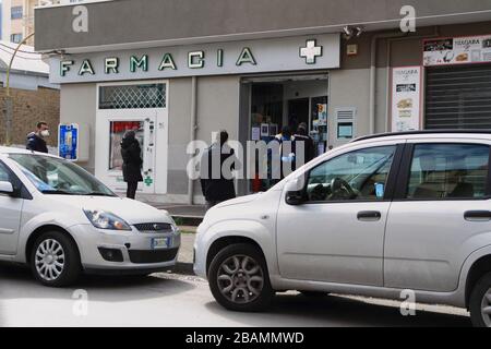 Pagani,sa,Italie -28 mars 2020 :les gens qui font la queue en dehors d'une pharmacie pour acheter des médicaments et des produits en vente libre observent les distances de sécurité establishis Banque D'Images