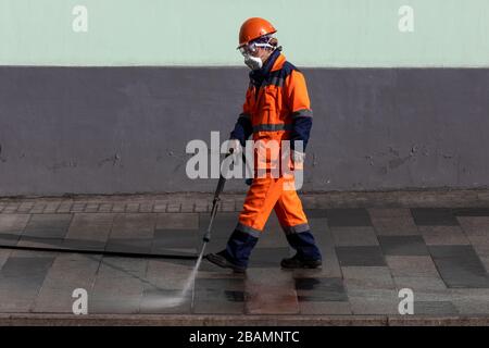 Moscou, Russie. 28 mars 2020 un nettoyeur de rue utilise un jet de lavage à l'électricité avec des désinfectants pour nettoyer le pavé dans le centre de Moscou pendant la pandémie de coronavirus COVID-19 en Russie. Les rues et les autres zones publiques sont nettoyées et désinfectées pour contrer la propagation du nouveau coronavirus. Banque D'Images