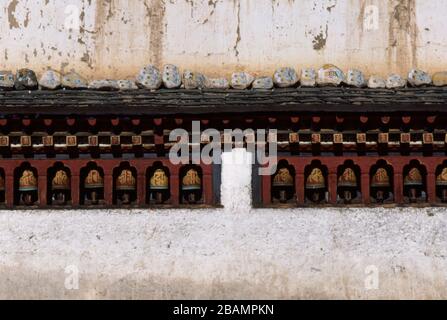 Roues de prière intégrées dans un mur de Paro Dzong, Bhoutan. Les roues du tambour sont pivotées à la main pour produire un son qui renchire le demandeur. (19-10-89) BX82 Banque D'Images