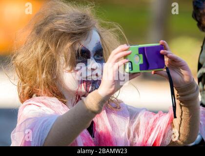 Saint John, Nouveau-Brunswick, Canada - 21 octobre 2017 : promenade Zombie. Une jeune fille zombie prend un selfie avec un téléphone. Banque D'Images