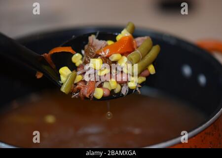 Grande cuillère pour préparer de la soupe de bœuf et de légumes maison à partir d'un pot. Gros plan. Coloré. Banque D'Images