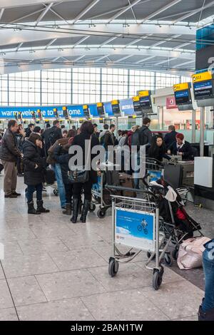 Terminal 5, aéroport d'Heathrow, Londres. Les passagers attendent en ligne et font la queue au comptoir d'enregistrement des bagages. Banque D'Images