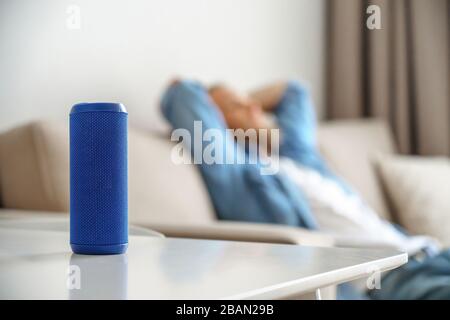 Petite enceinte portable sur la table avec salon pour homme écoutant de la musique dans une maison intelligente. Banque D'Images