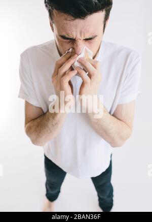 L'homme utilise du tissu pour essuyer les sofles de son nez. Guy avec symptôme d'allergie. Isolé sur fond blanc. Émotion humaine négative, sensation d'expression faciale Banque D'Images