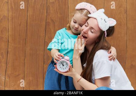 Maman avec une petite fille dans le sommeil masque yawn et se câlin l'un l'autre. Gardez une alarme près de la tête. Temps de sommeil. Bonne nuit et bon matin. Bref du matin Banque D'Images