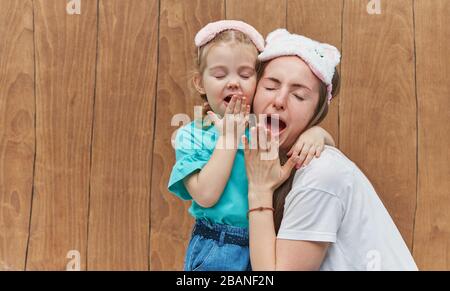 Maman avec une petite fille dans le sommeil masque yawn et se câlin l'un l'autre. Gardez une alarme près de la tête. Temps de sommeil. Bonne nuit et bon matin. Bref du matin Banque D'Images