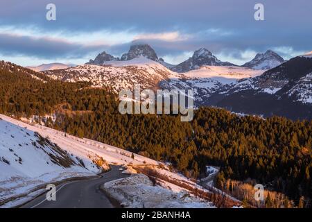 Les trois sommets des montagnes de Teton dans le Wyoming juste visible à travers les nuages avant le coucher du soleil. En dessous d'une route sinueuse étroite mène au Grand Targhee Banque D'Images