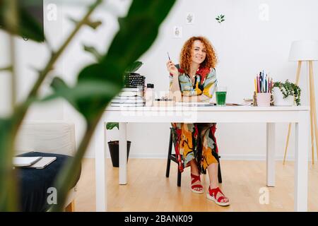 Belle fille assise à la table dans un atelier créatif Banque D'Images