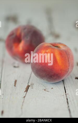 Deux pêches fraîches et mûres sur fond blanc en bois Banque D'Images