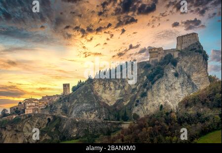 Vue sur le coucher du soleil de la forteresse de San Leo sur une colline avec des tours de canon en Italie Banque D'Images
