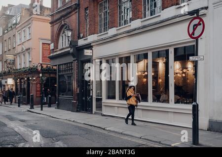 Londres, Royaume-Uni - 06 mars 2020: Rangée de cafés et restaurants à Soho, un quartier du centre de Londres célèbre pour les bars et les restaurants, femme marchant devant, motion Banque D'Images