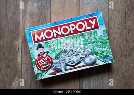 Boîte de jeux de société Monopoly isolée sur un fond de bois. Le jeu de société classique de négociation rapide de biens est actuellement publié par Hasbro. Banque D'Images