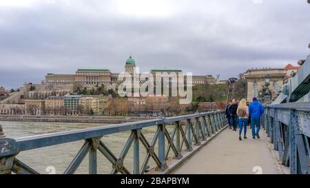 Budapest Hongrie 03 16 2019: Les touristes traversent le pont de la chaîne Szechenyi dans le fond du château de Buda Banque D'Images