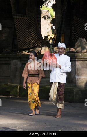 Hommes et femmes ouvriers de temple vêtus de vêtements traditionnels préparant l'arrivée touristique au Temple de l'eau Sainte près d'Ubud à Bali. Banque D'Images