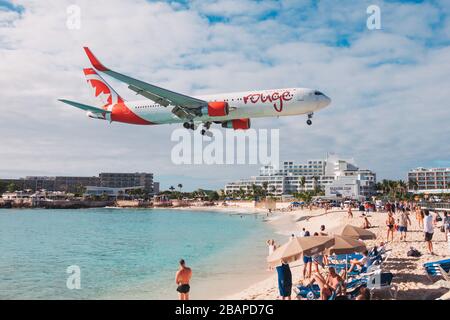 Un Boeing 767 d'Air Canada Rouge arrive sur terre au-dessus des touristes sur la plage de Maho, Saint-Martin Banque D'Images