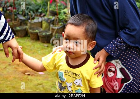 Image floue peu focalisée petite fille jouant avec son frère plus jeune dans le parc, Batang Indonésie, Banque D'Images