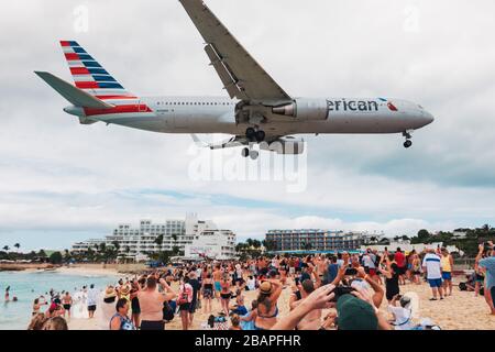 Un Boeing 767-300 ER d'American Airlines siffle sur une plage de Maho bondée de touristes d'un bateau de croisière, tout en atterrir à Sint Maarten Banque D'Images