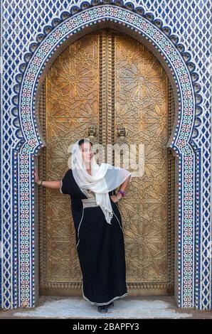 Une jeune femme dans un voile devant la porte du Palais Royal à Fes Banque D'Images