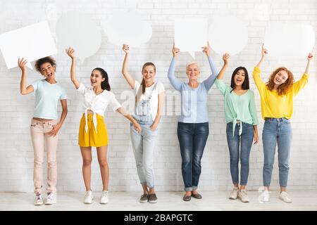 Femmes tenant vide des bulles de parole se tenant sur le mur blanc à l'intérieur Banque D'Images