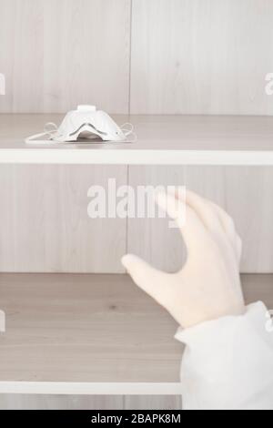 Main avec gant médical prenant la dernière chirurgie ou masque médical de visage hors de rack Banque D'Images