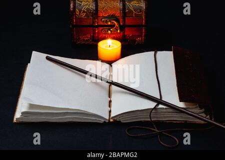 Image d'un livre magique ouvert et d'une baguette sur la table dans la pièce sombre. Banque D'Images