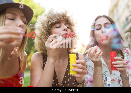 Les jeunes femmes soufflent des bulles de savon à l'extérieur Banque D'Images