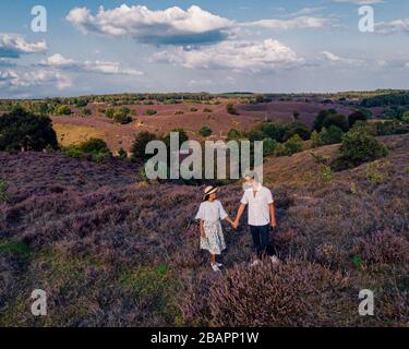 Couple marchant dans les prés, Posbank parc national Veluwezoom, fleurs champs chiné pendant lever du soleil à la Veluwe aux Pays-Bas, collines violettes Banque D'Images