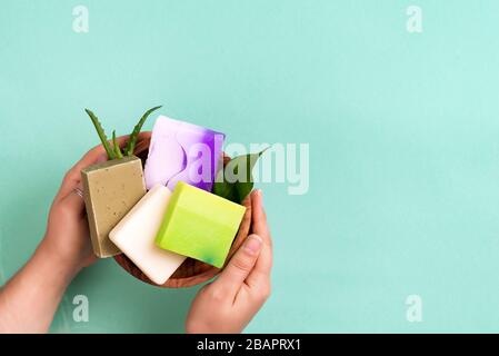 Les mains de femme tenant la barre de savon de couleur biologique naturelle sur fond bleu. Mode de vie sain, beauté, soins de la peau. Concept de maison zéro déchet. Banque D'Images