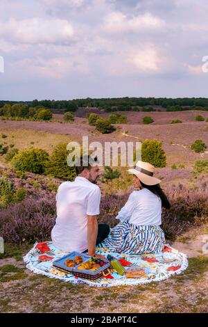 Couple marchant dans les prés, Posbank parc national Veluwezoom, fleurs champs chiné pendant lever du soleil à la Veluwe aux Pays-Bas, collines violettes Banque D'Images