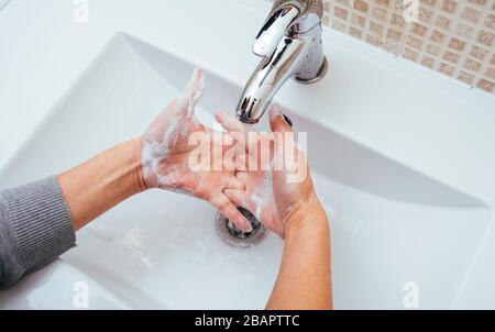 Femme se lavant les mains avec du savon et de l'eau dans la salle de bains à la maison. Nettoyage de l'hygiène des mains pour la prévention des épidémies de coronavirus. Protection contre la pandémie du virus Corona Banque D'Images