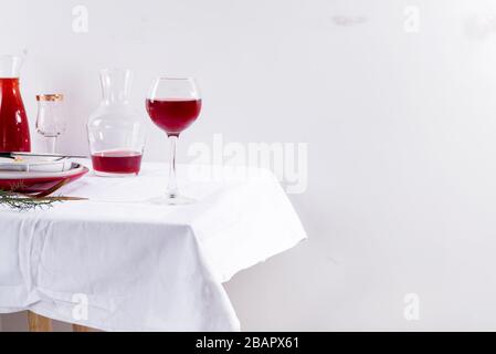 vin rouge dans un verre de vin, un décanteur et une table avec des ombres isolées sur fond textile blanc Banque D'Images