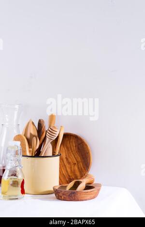 Ensemble en bois d'ustensiles de cuisine dans une tasse en fer avec plaques en bois sur une table en textile blanc. Appareils de cuisson. Zéro déchet Banque D'Images