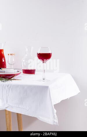 vin rouge dans un verre de vin, un décanteur et une table avec des ombres isolées sur fond textile blanc Banque D'Images