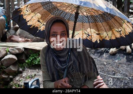 Place du marché. Déchargent. Les montagnes du Simien. Le nord de l'Éthiopie. Une fille chargé de bois de chauffage à l'écorcer marché. A écorcer quelques boutiques et d'échoppes où Banque D'Images